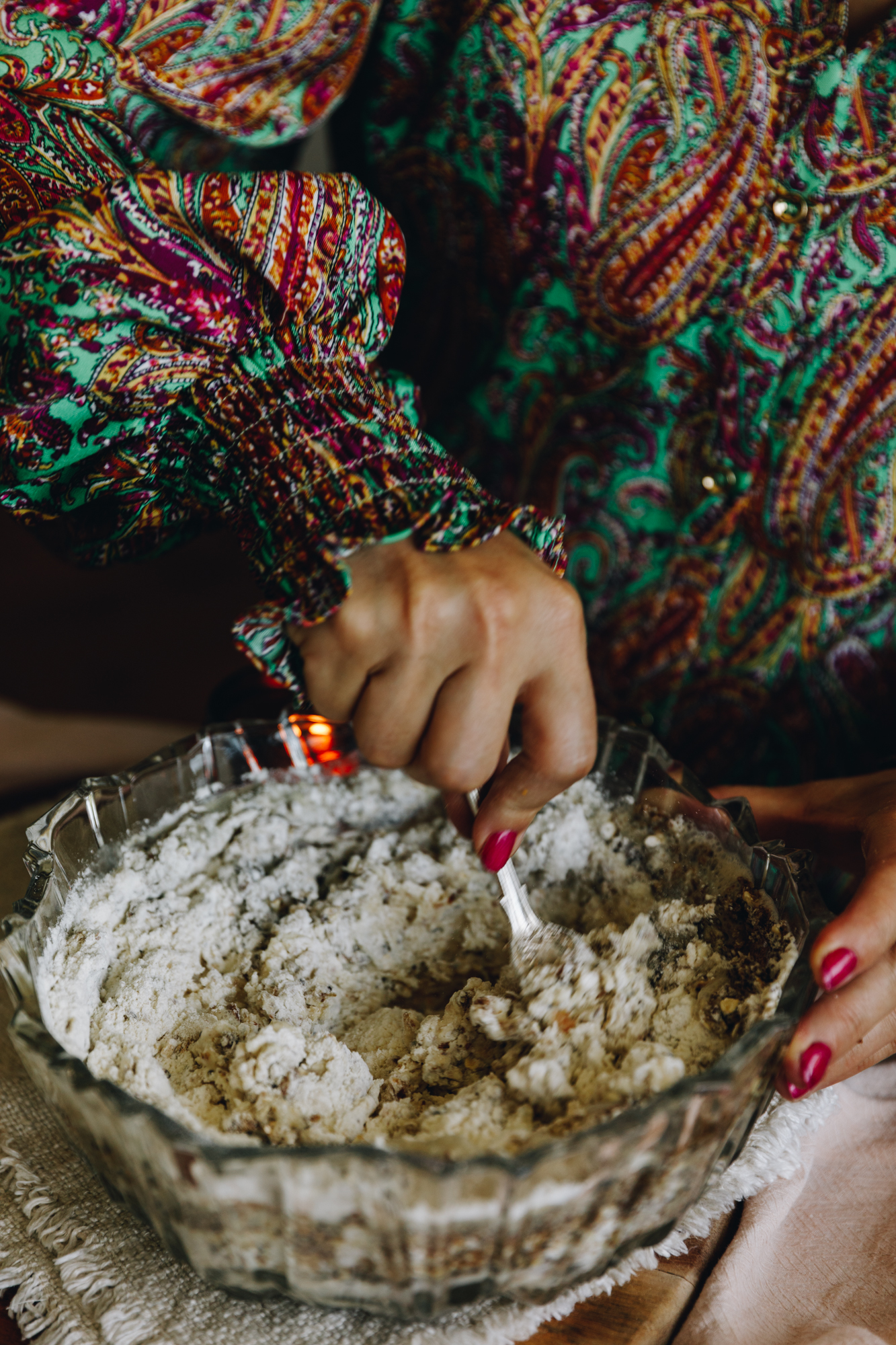 A hand with a colourful jumpsuit is mixing together the ingredients of the no-seeded oat bread.