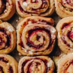 A flatlay shot shows freshly baked Custard and Raspberry Scrolls sitting in a tray.