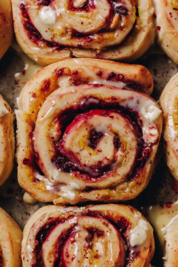 A flatlay shot shows freshly baked Custard and Raspberry Scrolls sitting in a tray.