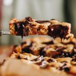 Close up of pistachio chocolate cookie slice with melty chocolate dripping from the slice.