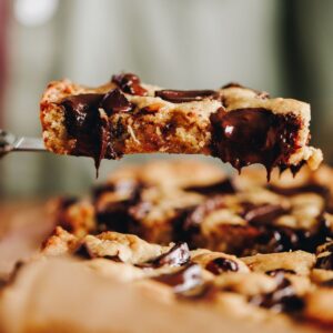 Close up of pistachio chocolate cookie slice with melty chocolate dripping from the slice.