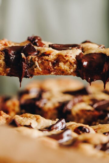 Close up of pistachio chocolate cookie slice with melty chocolate dripping from the slice.