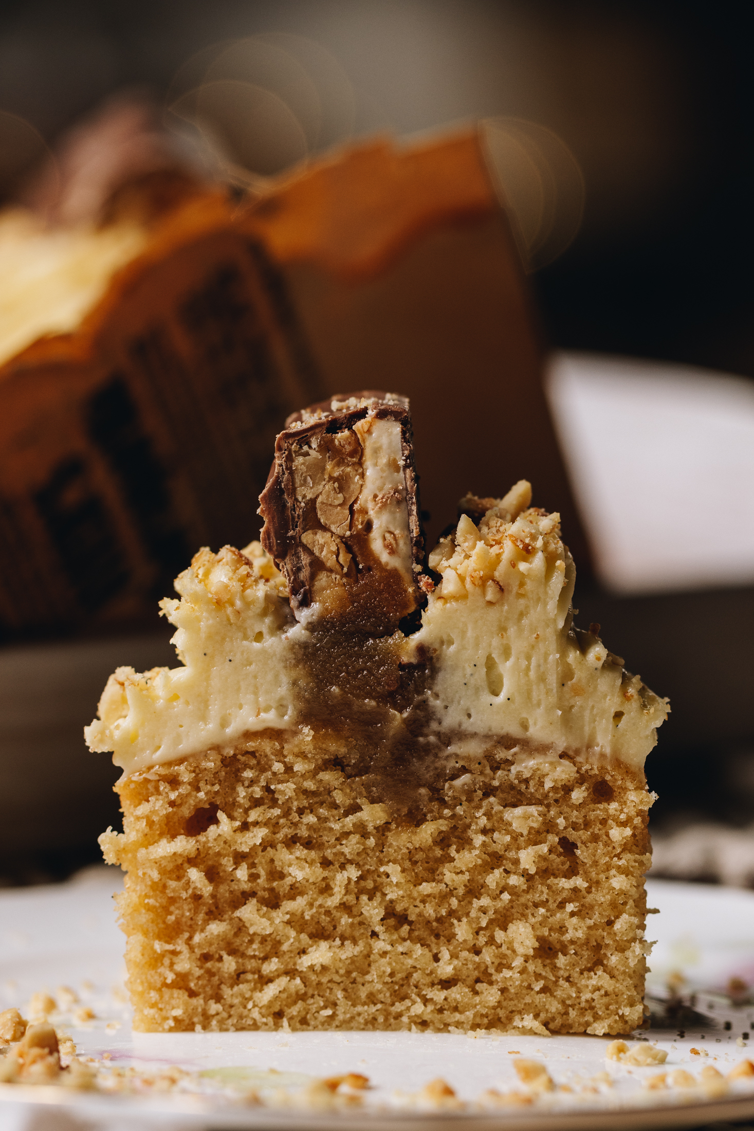 A Brown Butter Vanilla Cupcake has been sliced open to reveal the cake, gooey caramel centre, cream cheese frosting and snickers top.