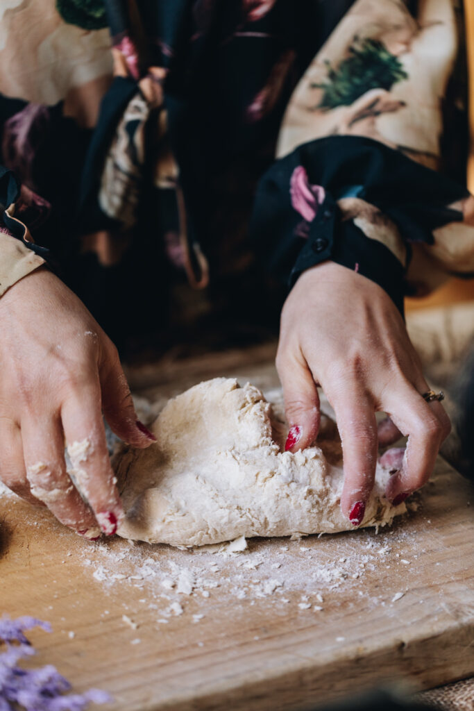 The sweet Lemon Pastry dough is being kneaded on a wooden board with Naomi's hands. 