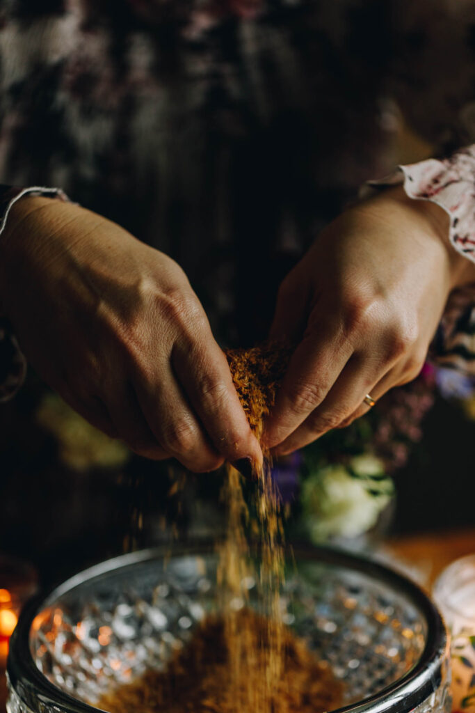Close up of hands that are crushing the weetbix in the bowl, the crushed pieces are falling in to a glass bowl with silver trim. 