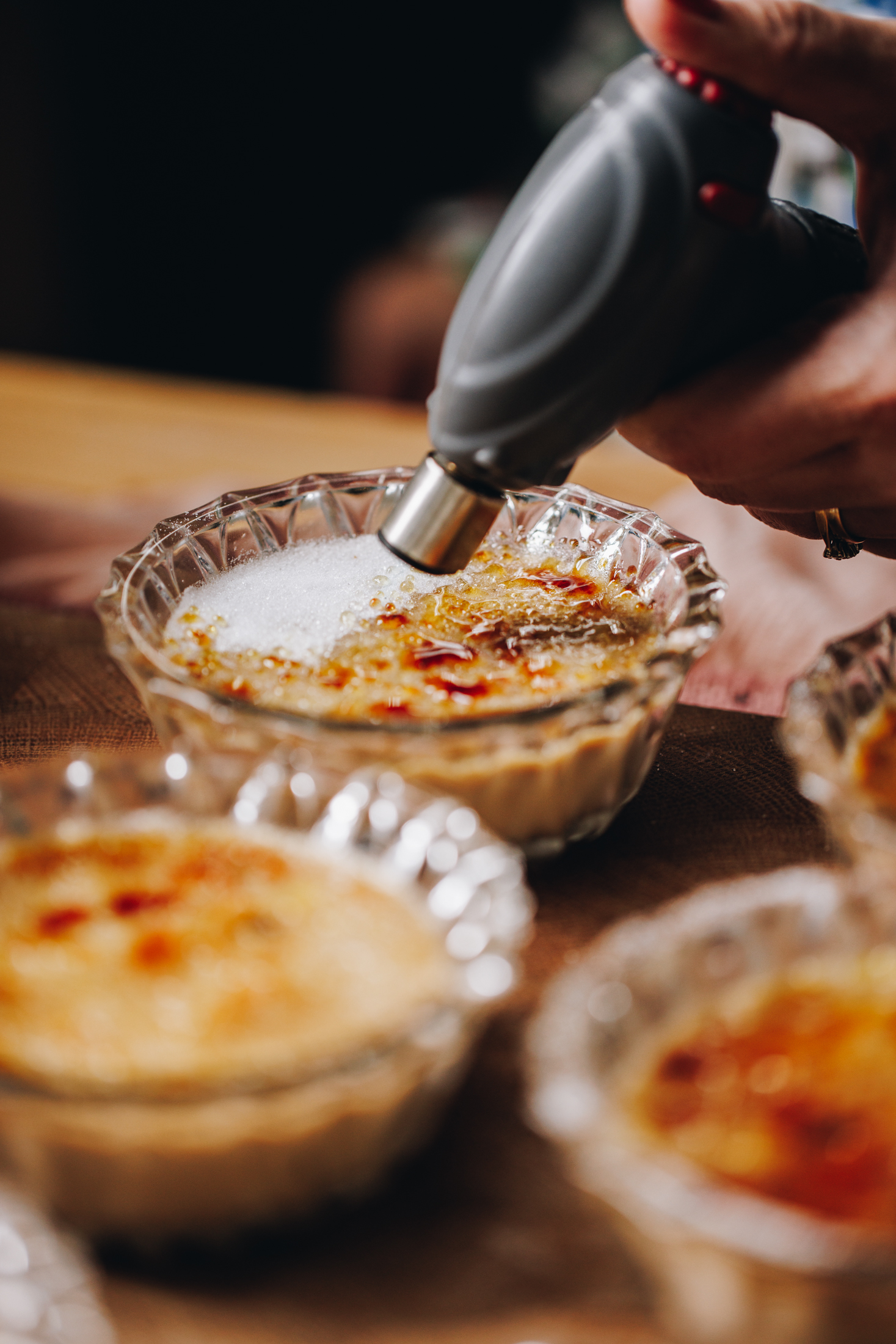 A close up of baked Chai Créme Brûlée shows sugar being caramelised with a chef's torch. 
