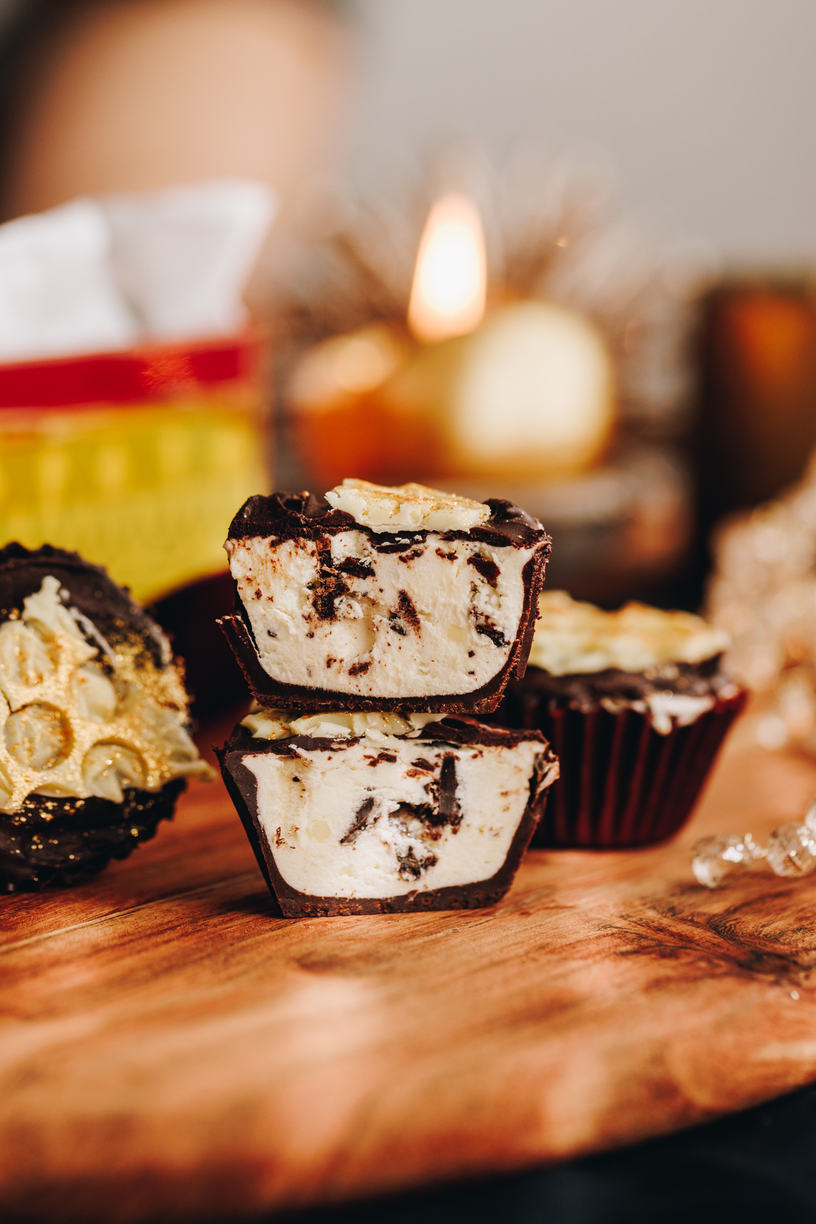 no-bake creamy peppermint cups are cut open and stacked on each other. It shows the creamy peppermint filling. A candle burns in the background with an old school baking tin. 