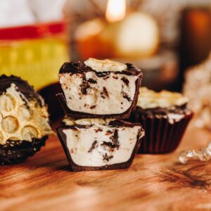no-bake creamy peppermint cups are cut open and stacked on each other. It shows the creamy peppermint filling. A candle burns in the background with an old school baking tin.
