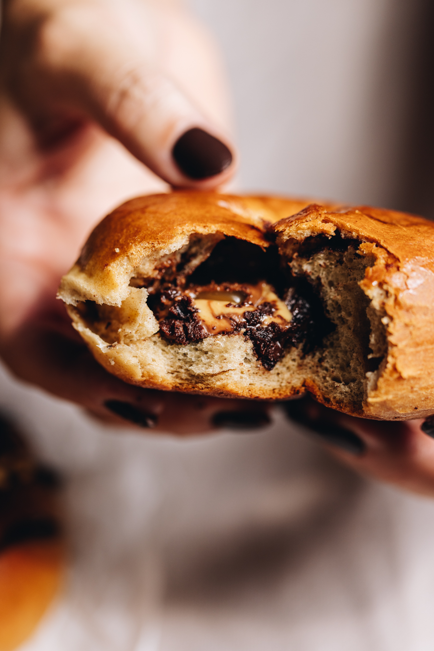 A gooey chocolate baked doughnut is held in the air. It has had a couple of bites removed and it reveals a gooey chocolate inside.