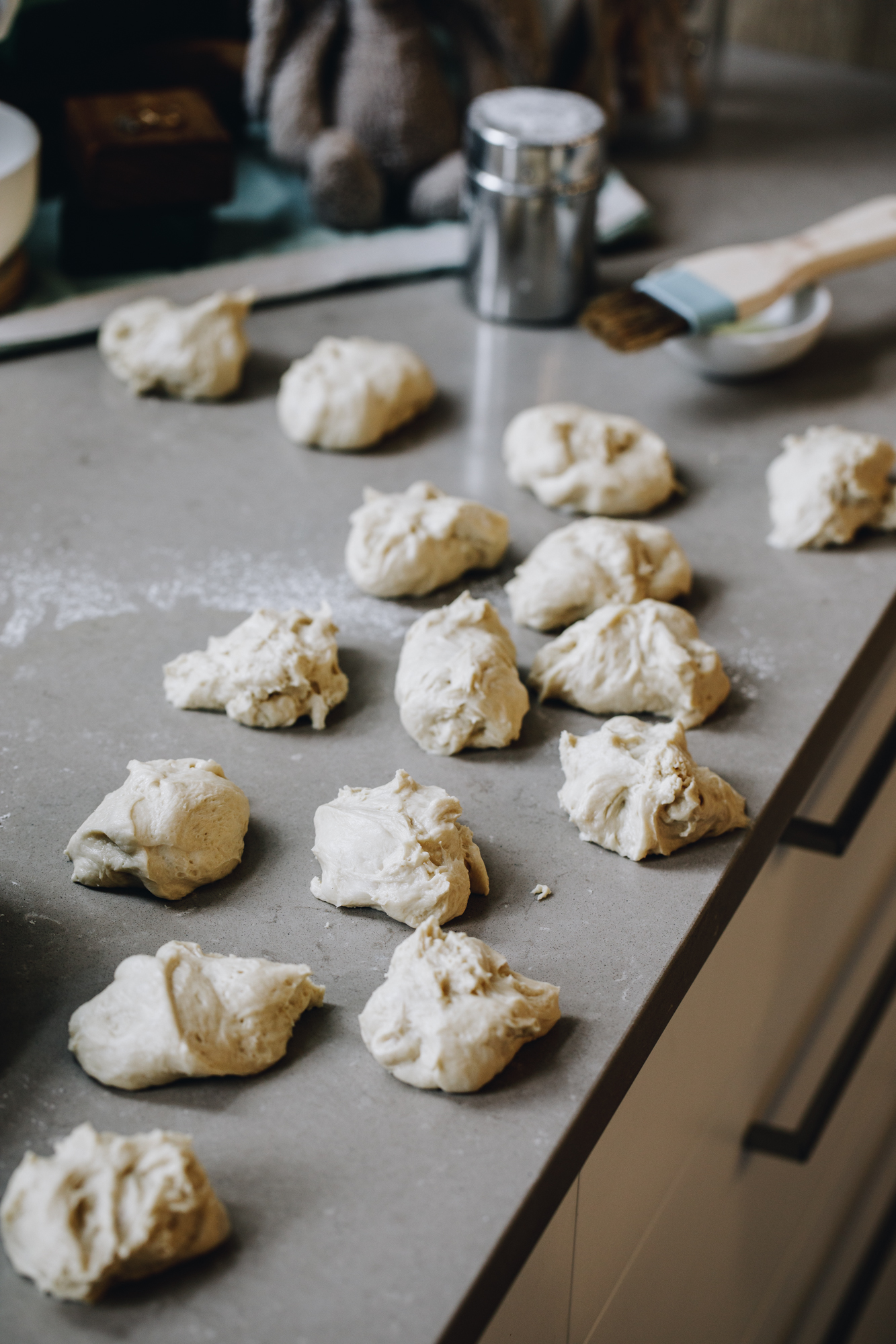 On a grey stone bench is 12 dough balls that have not been shaped.