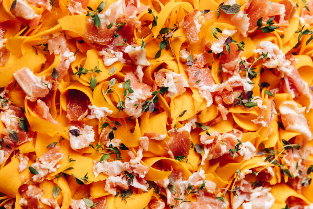 A close up of pumpkin ribbons, streaky bacon, fresh thyme are seen. They are the uncooked filling of my Creamy Pumpkin Tart recipe.