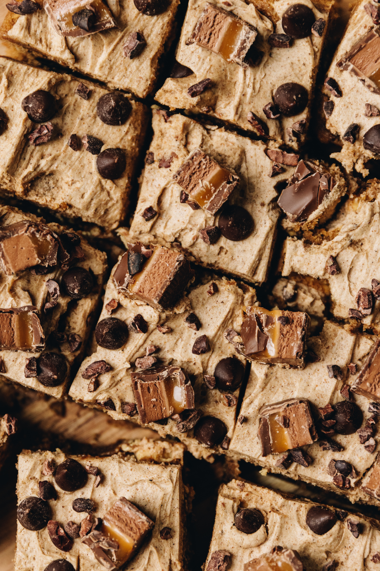 Sliced coffee chocolate blondies with walnuts decorated with sliced moro bar, chocolate drops and cacao nibs.