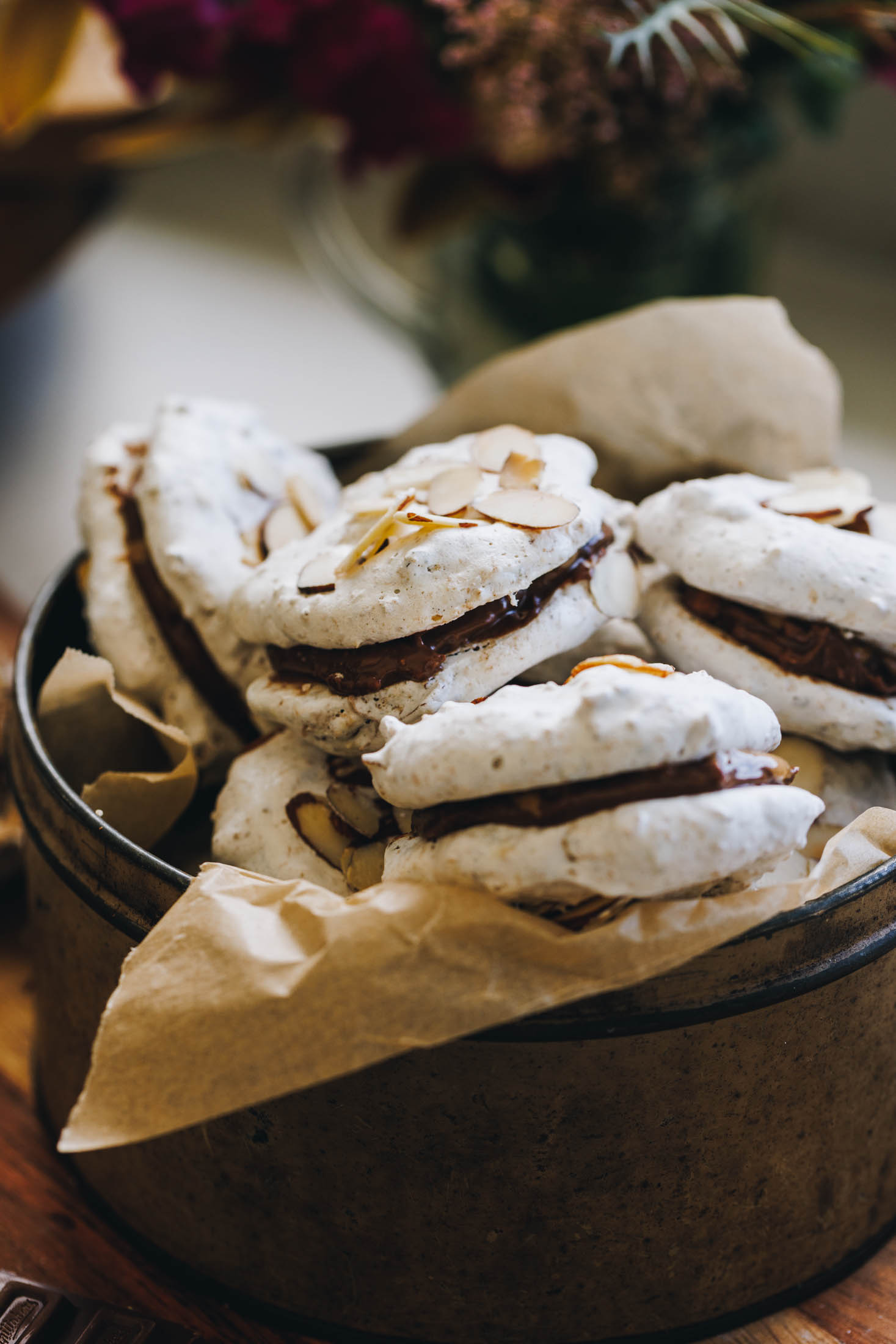 Filled forgotten cookies in a rustic biscuit tin lined with baking paper and stacked inside.