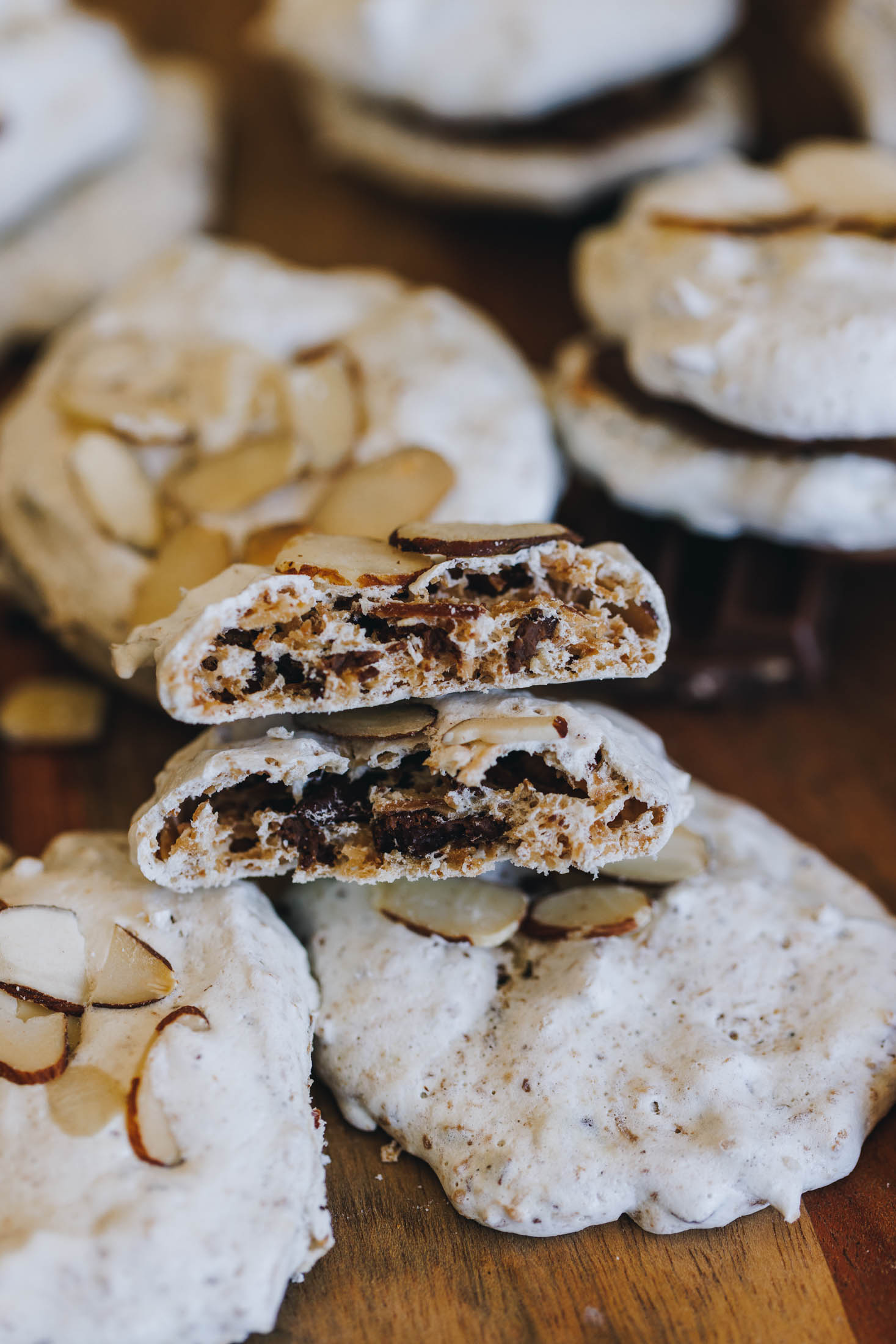 Gluten-free forgotten cookies on a wooden board with one broken open showing the soft interior.