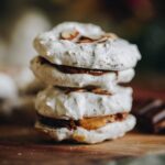 Gluten-free forgotten cookies on a wooden board with one broken open showing the crunchy interior.