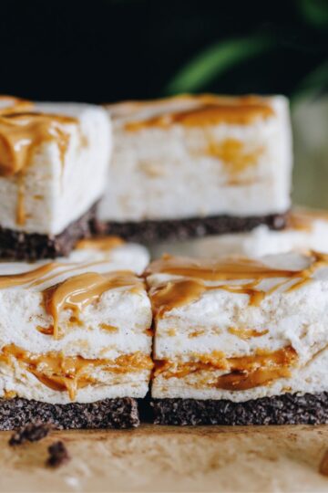 No-bake peanut butter marshmallow slice stacked on baking paper, flowers in the background.