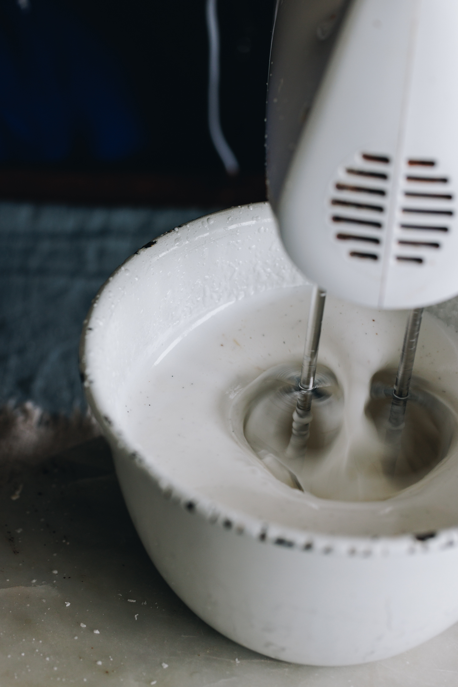 Marshmallow mixture whipping in a white bowl with a white hand mixer. 