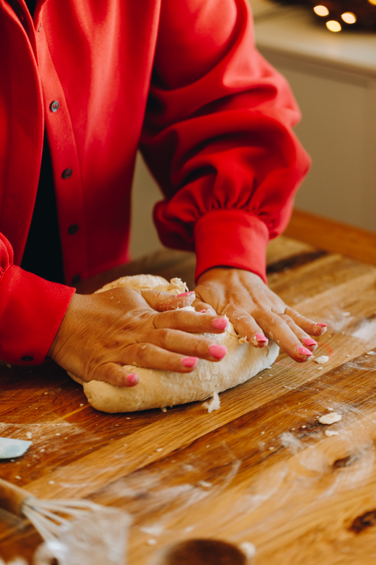 Hands kneading dough on a floured wooden table. 