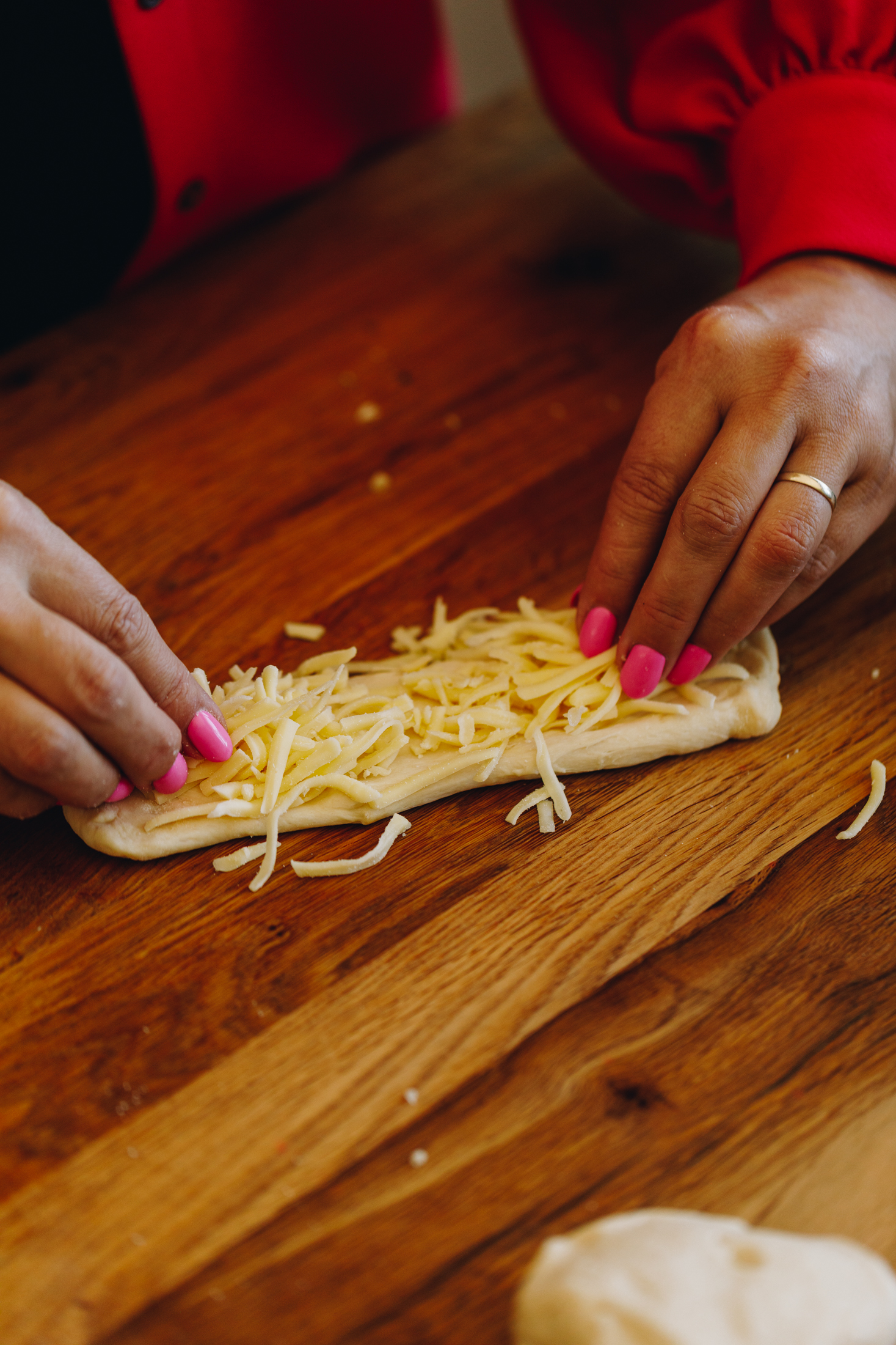 Grated cheese stuffed into bread dough on a wooden table. 