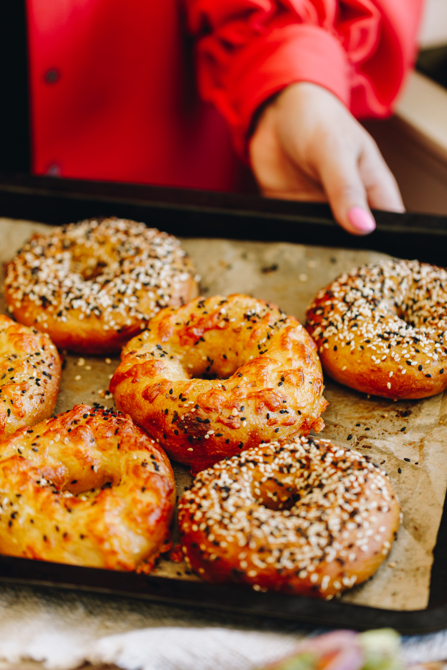 A tray of seed and cheese bagels on a tray being held. 