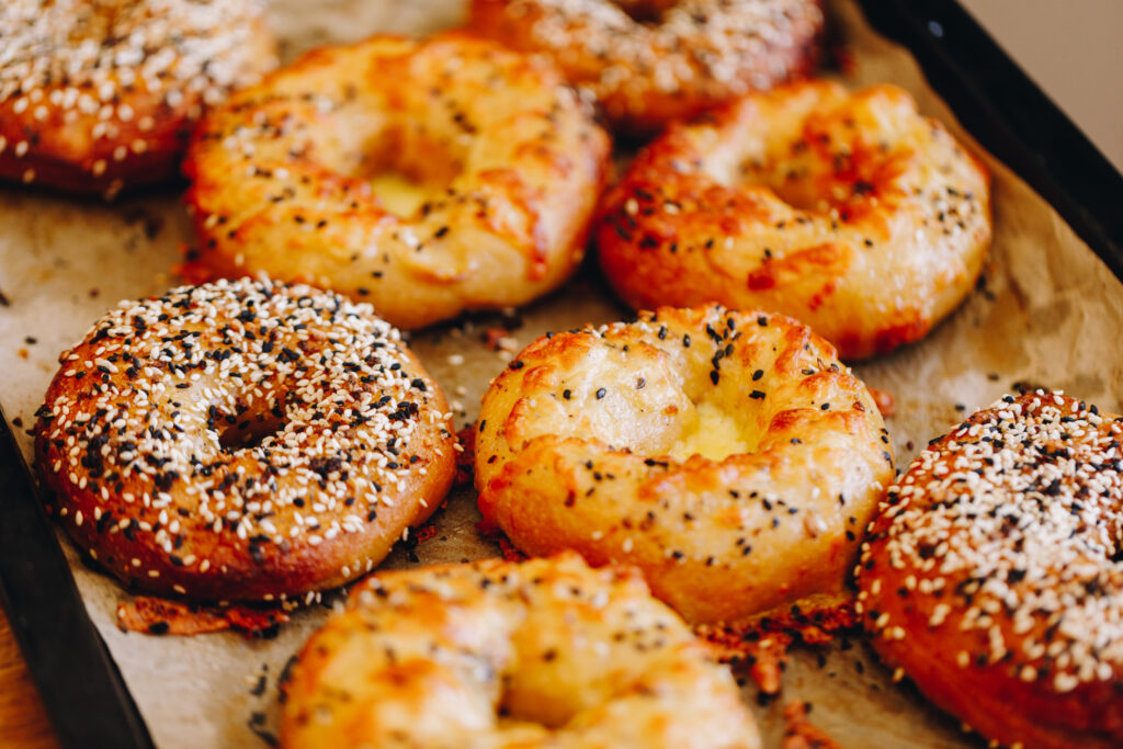 Freshly baked bagels with cheese on some and bagel seed mix on others.